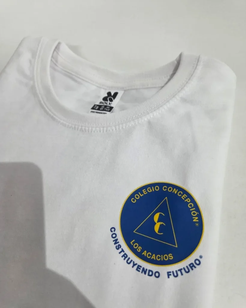 Polera institucional con el escudo del colegio aplicado en tamaño pequeño sobre el pecho