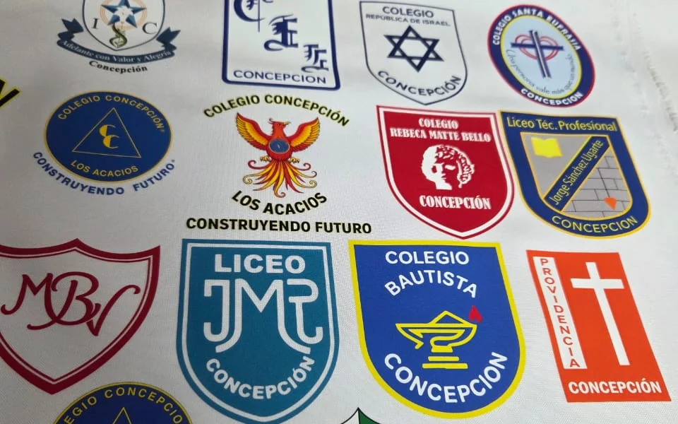Paño DTF impreso con los escudos de varios colegios de Concepción, listos para aplicar