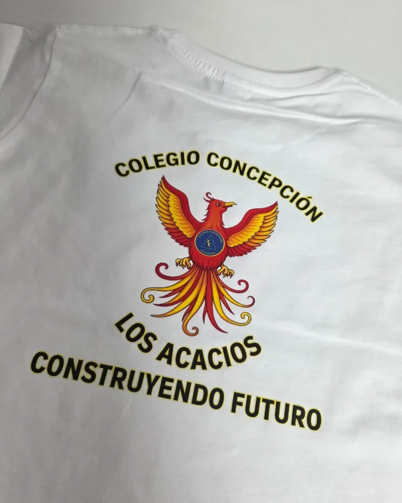 Polera institucional blanca con el escudo del colegio estampado a gran tamaño en el pecho