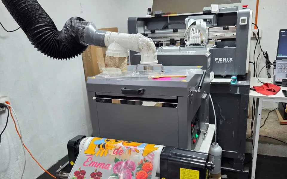 Impresora DTF de Fénix Creations sacando un paño impreso a todo color con diseños de rosas