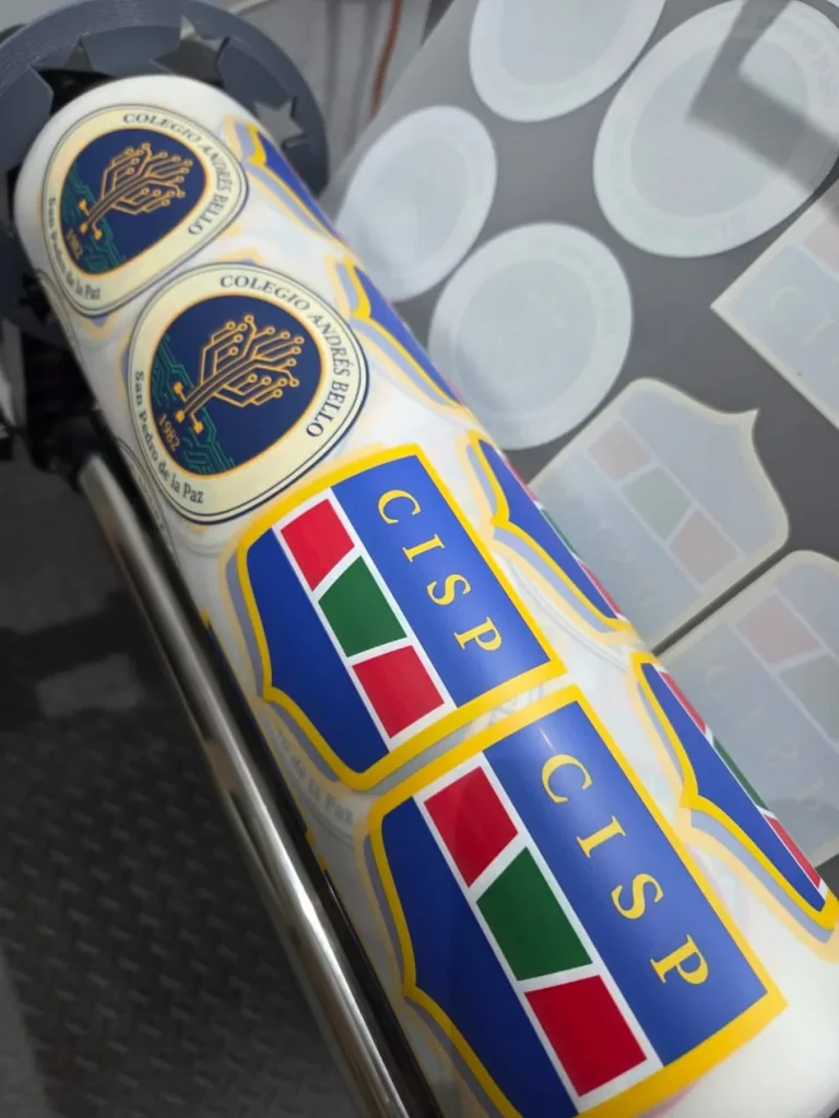 Rollo DTF impreso con el escudo de un colegio repetido, listo para aplicar por unidad