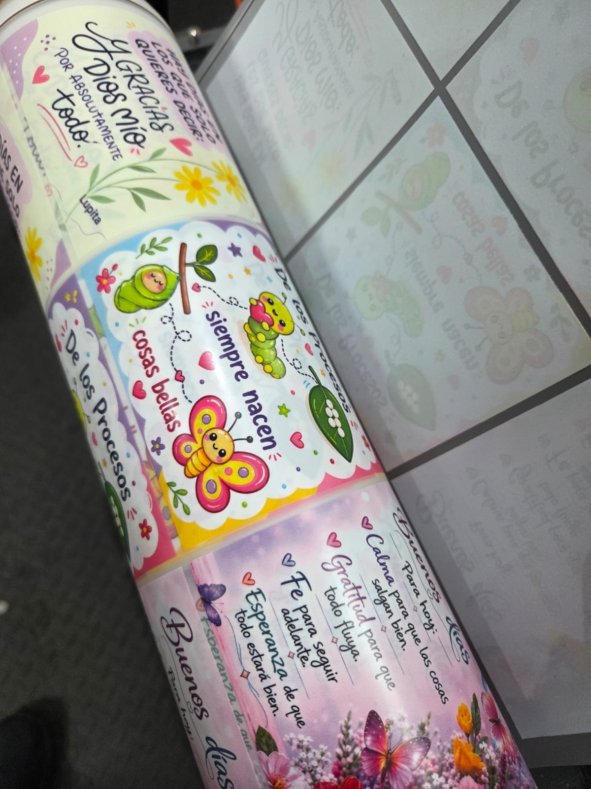 Rollo de DTF impreso con diseños de frases y flores en colores pastel, listo para cortar y aplicar.